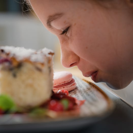 Child smells a plate of cake in the children's hotel