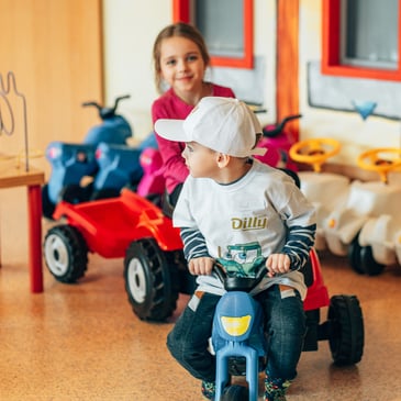 Mädchen und Bub auf einem Dreirad im Kinderhotel