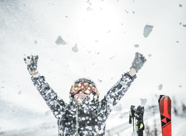 Kind wirft Schnee in die Höhe