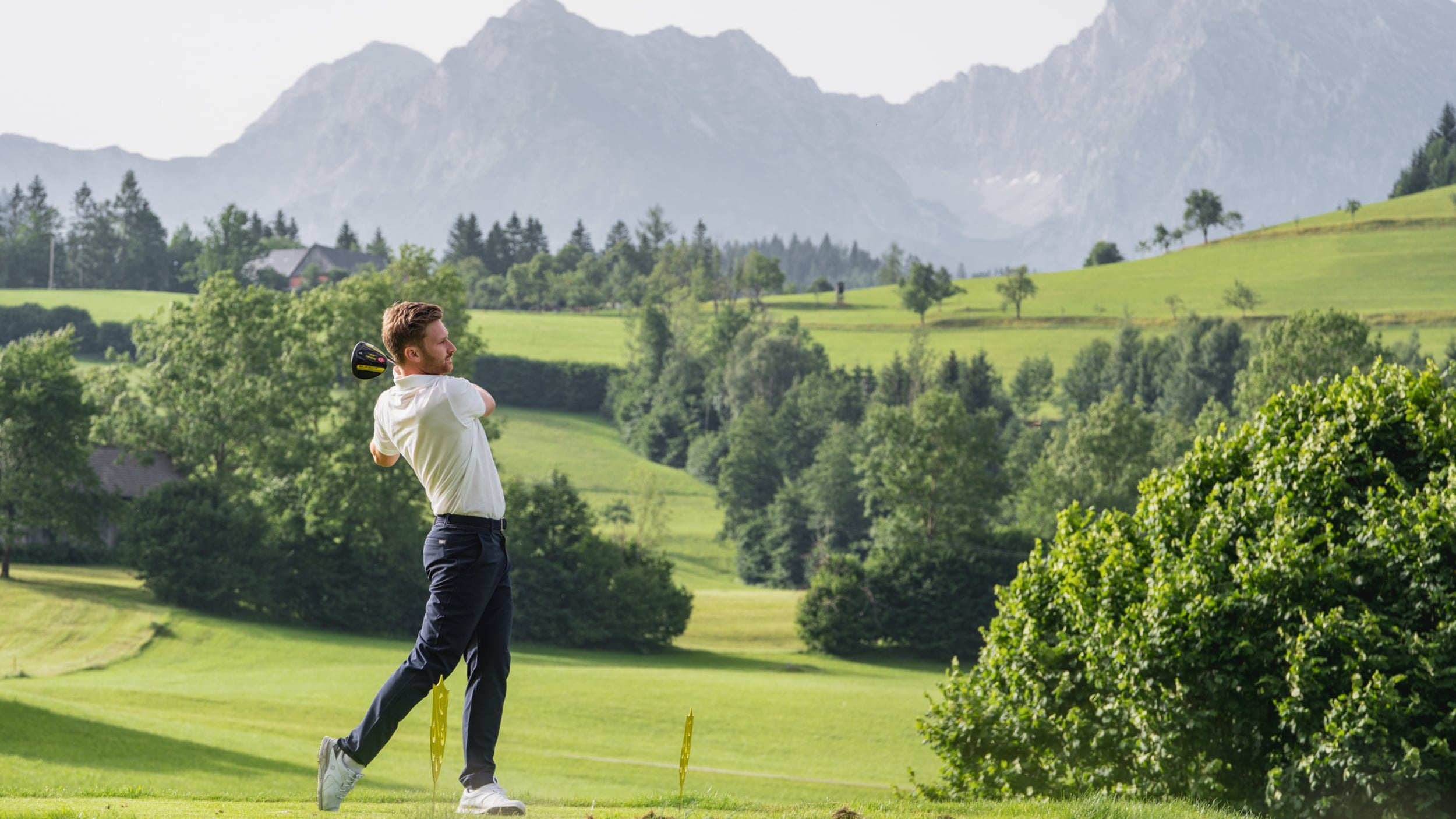 Golfers teeing off on the golf course with mountain views in Windischgarsten