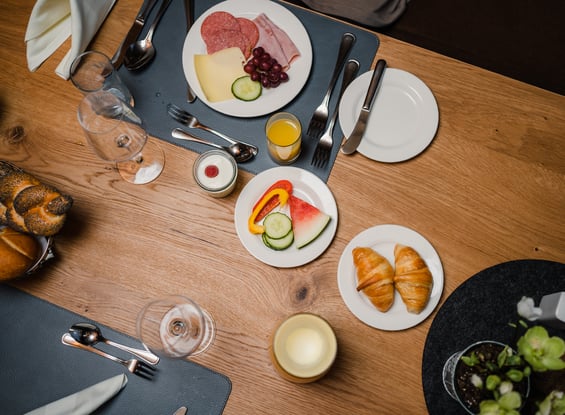 Set breakfast table with sausage, cheese, vegetables & croissants