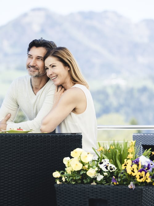 Young couple in summer on the terrace of the Wellnesshotel Dilly in front of the mountains