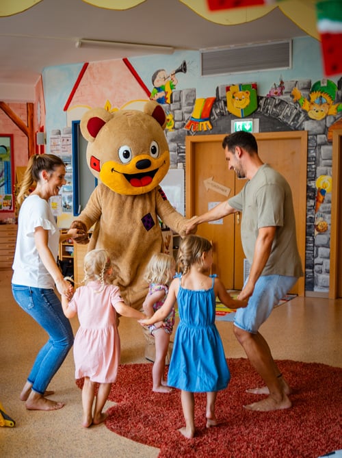Tanzende Kinder mit Eltern und Luki Bär im Kinderhotel Österreich