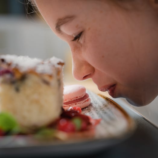 Kind riecht an einem Kuchenteller im Kinderhotel