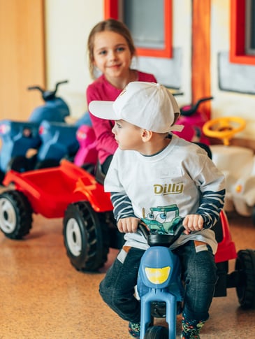 Mädchen und Bub auf einem Dreirad im Kinderhotel