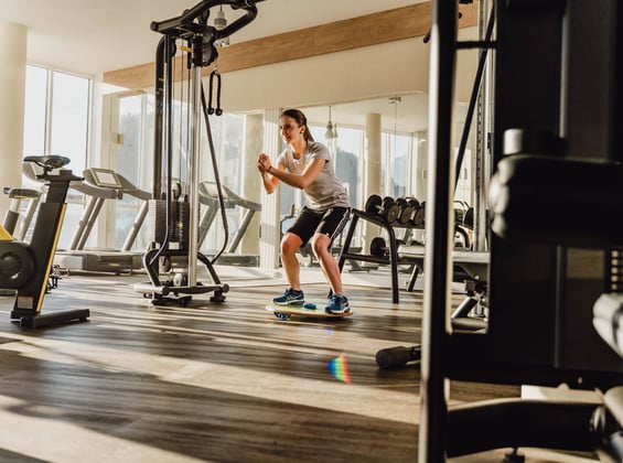 Frau macht Kniebeugen im Fitnessraum des Sporthotels in Windischgarsten