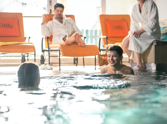 Father lying on a lounger and watching children playing in the indoor pool