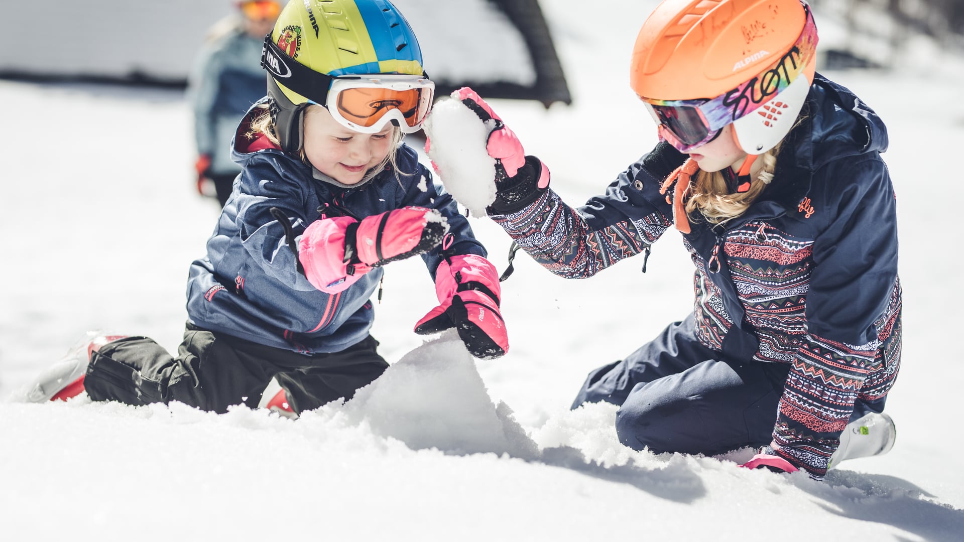 Kinder mit Schihelm spielen im Schnee