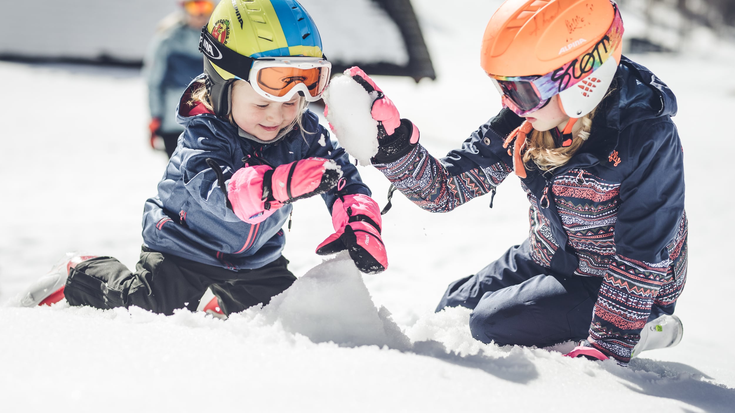 Kinder mit Schihelm spielen im Schnee