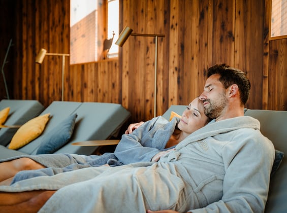 Couple in bathrobes cuddling on a comfortable lounger in the relaxation room